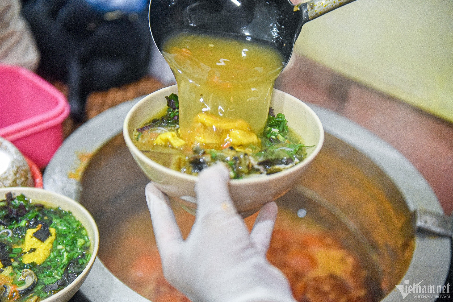 Thực khách đang thưởng thức bún ốc tại một quán ăn nhỏ trong ngõ chợ Đồng Xuân đông đúc
